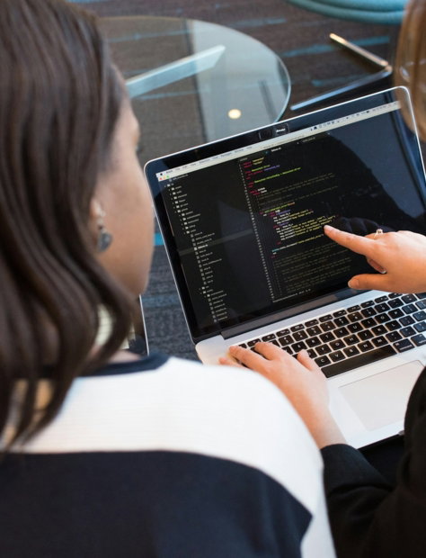 woman using MacBook Pro with person in white top